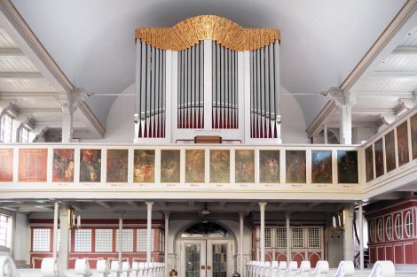 Blick in hellen Kirchenraum mit Sitzreihen und Orgel auf Empore