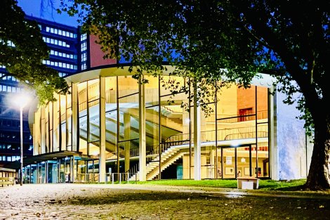 Ansicht eines Gebäudes mit Glasfassade am Abend im Schein einer Straßenlaterne