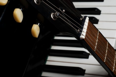 Nahaufnahme von einer Gitarre, die an einem Klavier lehnt