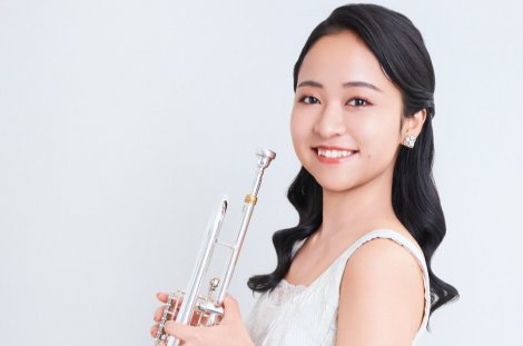 Musikerin mit Trompete in der Hand, lachend