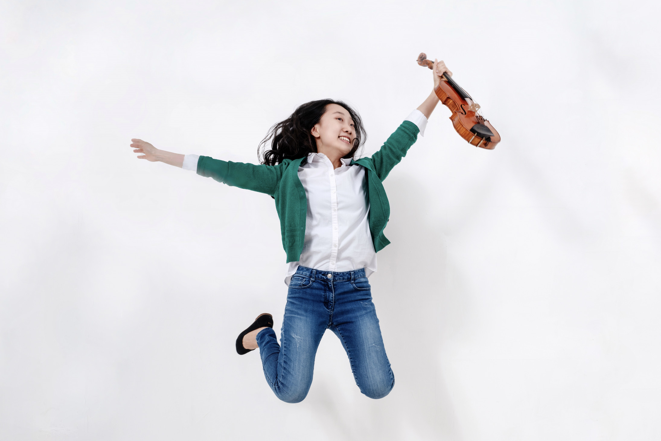 Foto von einer springenden Frau mit Violine in der Hand